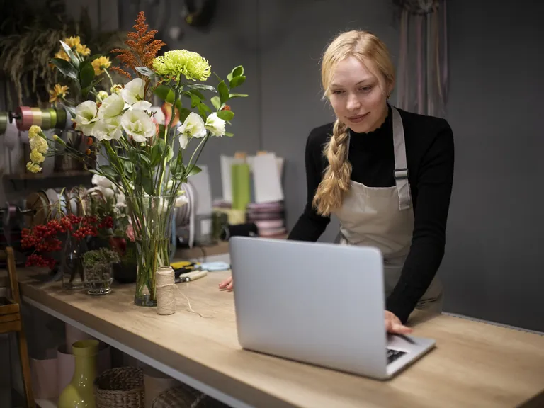 A florist working on a laptop at her counter