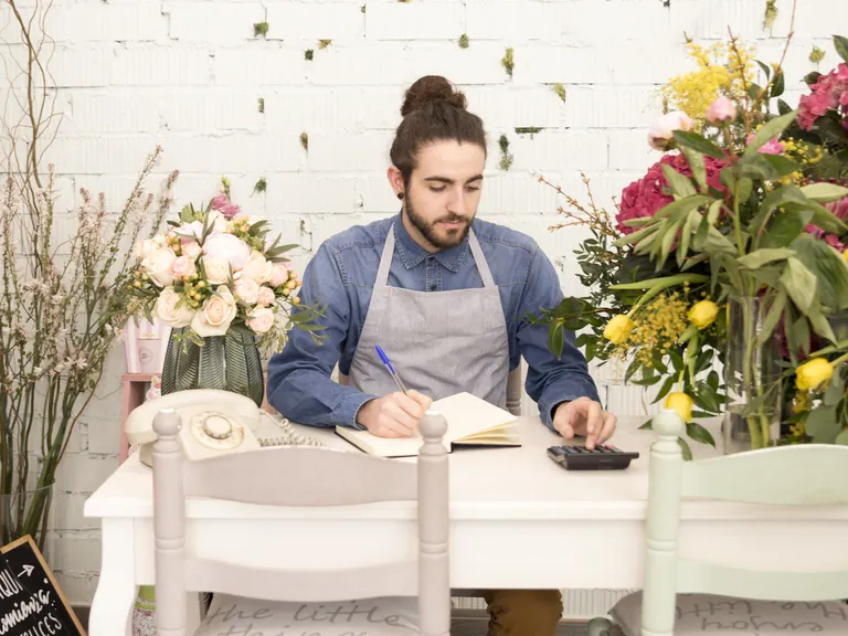 A man working through figures at a table in a flower shop